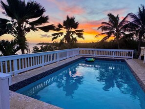 A swimming pool with a white deck and a view of the sunset over the ocean. - Luxury 1 bedroom Waterfront Villa with Private Pool and Spacious Deck (Frederiksted)