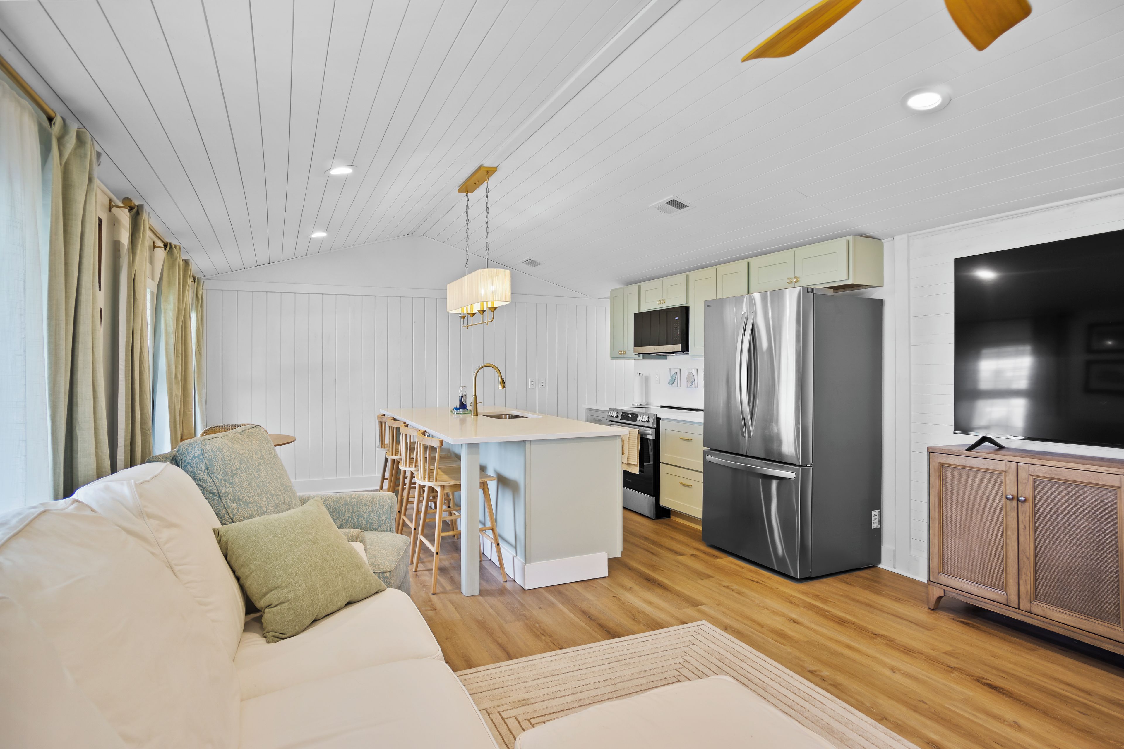 A modern kitchen with a central island, stainless steel appliances, and light-colored cabinetry.