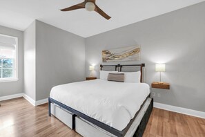 A bedroom with a bed, a ceiling fan, a painting, and bedside lamps. - Village at Blue Mtn Beach 625 - Close to beach located in 30A (Santa Rosa Beach)
