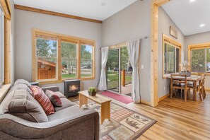 A cozy living room with a sofa, a fireplace, and large windows.