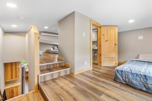 A bedroom with a wooden staircase, a bed with a blue blanket, and a wooden wardrobe.