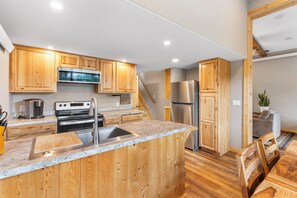 A modern kitchen with wooden cabinets, stainless steel appliances, and a marble countertop.