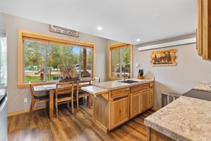 A kitchen with wooden cabinets, a marble countertop, and a large window offering a view of the outdoors. - Family Cabin in Breckenridge Tiger Run Resort 5 min to Gondola (Breckenridge)