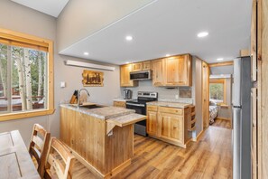 A modern kitchen with wooden cabinets, a built-in island, and a large window.