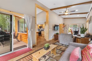 A spacious living area with a sofa, a coffee table, and a television. There is a sliding glass door leading to an outdoor patio with a table and chairs. - Family Cabin in Breckenridge Tiger Run Resort 5 min to Gondola (Breckenridge)