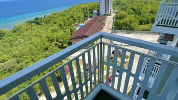 A balcony with a view of a coastal area, including a building and a clear sky.