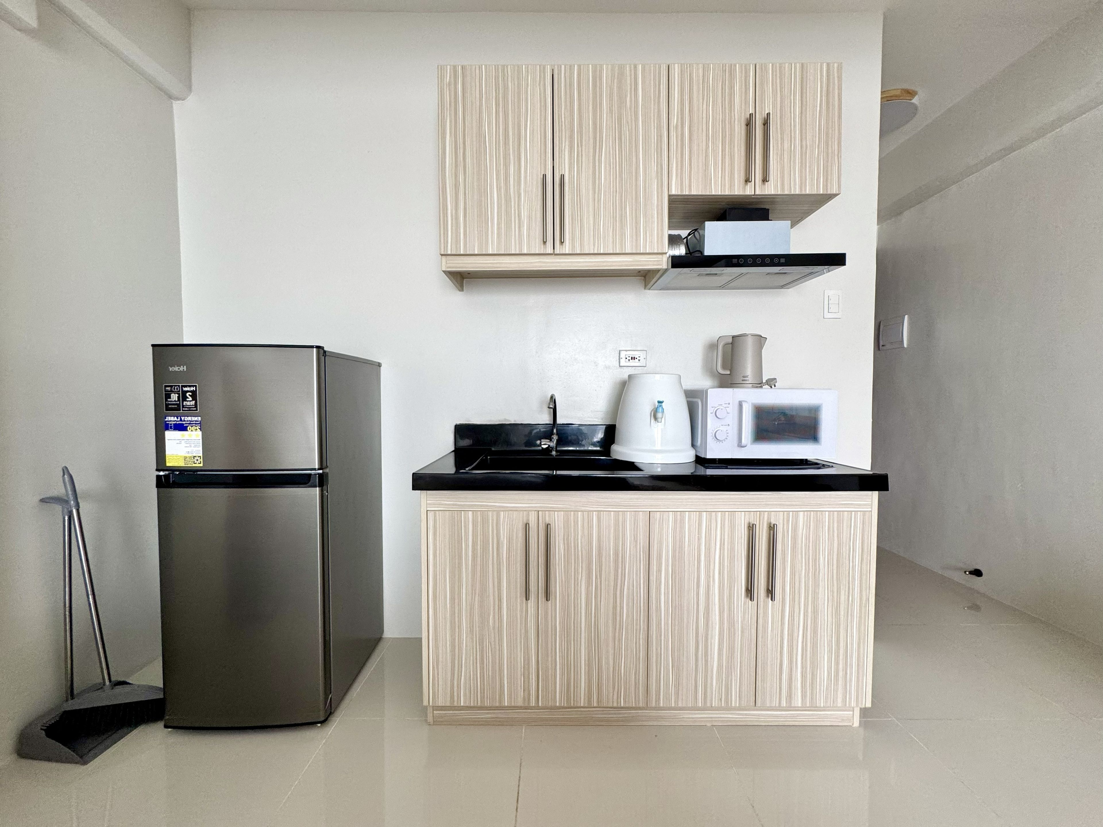 A compact kitchen with a stainless steel refrigerator, a microwave, and a coffee maker on the countertop.