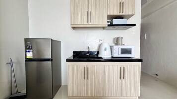 A compact kitchen with a stainless steel refrigerator, a microwave, and a coffee maker on the countertop.