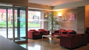 Um lobby com assentos vermelhos, uma mesa de centro e uma janela grande.