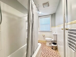 A bathroom with a bathtub, toilet, and window. - Spacious 3B2B home near JWU & Roger Williams Park (Providence)