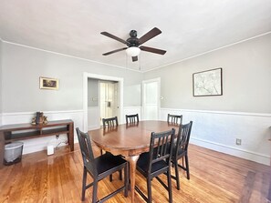 A dining room with a wooden table and chairs, a ceiling fan, and a framed picture on the wall. - Spacious 3B2B home near JWU & Roger Williams Park (Providence)