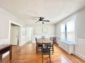 A dining area with a wooden table and chairs, a ceiling fan, and a window with blinds. - Spacious 3B2B home near JWU & Roger Williams Park (Providence)