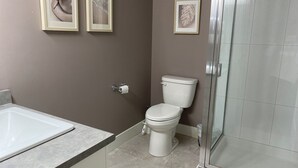 Un baño con bañera, inodoro y cabina de ducha de vidrio.