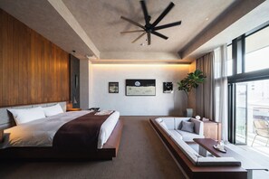 Moderni hotellihuone, jossa on suuri sänky, oleskelualue ja näkymä kaupunkiin.