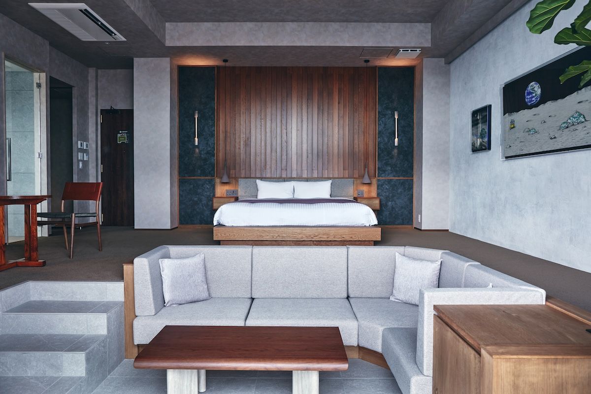 Quarto moderno com cama, sofá e mesa de centro de madeira.