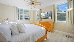 A bedroom with a bed, a ceiling fan, a dresser, a TV, and large windows. - Charming 3 Bedroom Apartment in Aventura - Cozy and Beautifull, Ideal for Family (Aventura)
