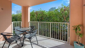 A balcony with a table and chairs, a potted plant, and a view of trees and buildings. - Charming 3 Bedroom Apartment in Aventura - Cozy and Beautifull, Ideal for Family (Aventura)
