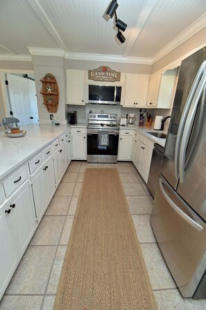 A kitchen with white cabinets, stainless steel appliances, a microwave, an oven, and a refrigerator. - Game Time Up (Upstairs Only) - Walk to the Beach (Garden City Beach)