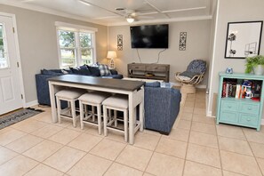 A modern living room with a bar area, a television, and a bookshelf. - Game Time Up (Upstairs Only) - Walk to the Beach (Garden City Beach)