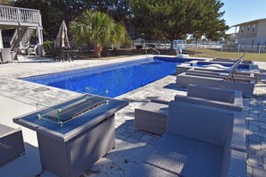 Piscina con sillones de descanso y zona de barbacoa techada.