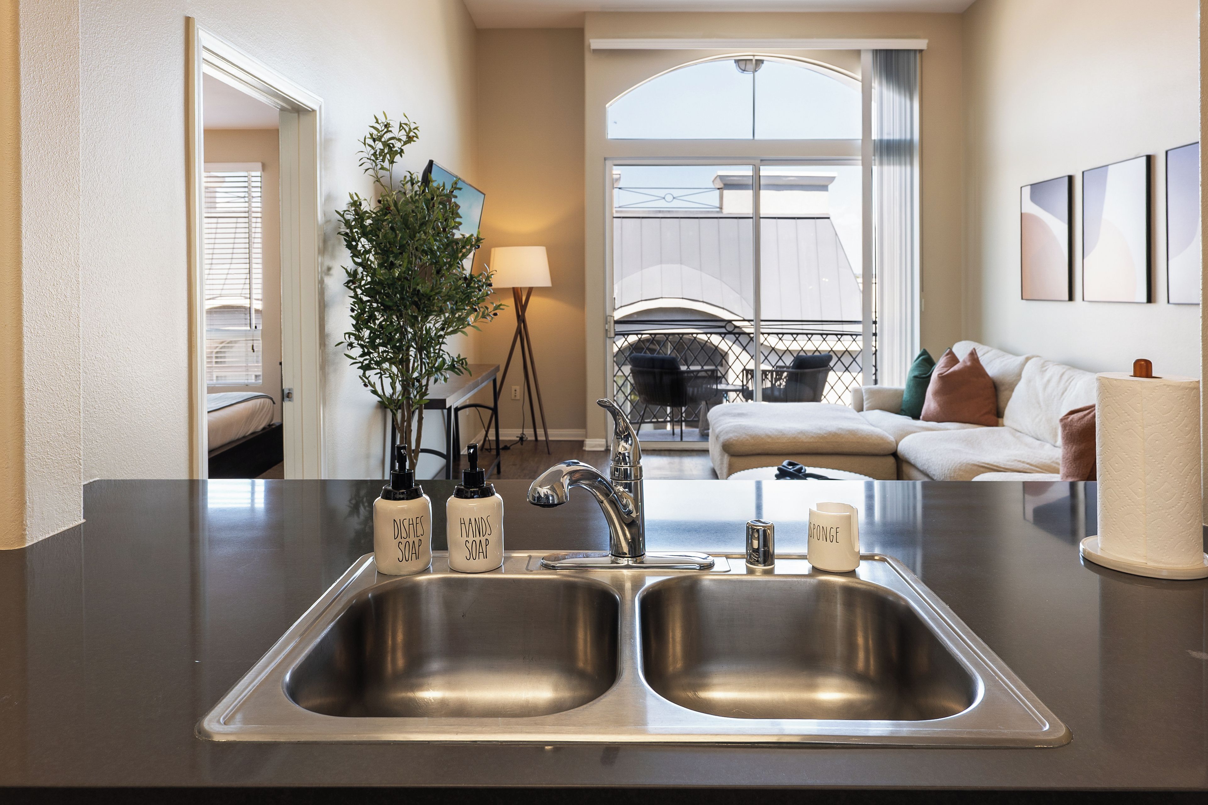 A modern kitchen with a double sink, two soap dispensers, and a single sponge.