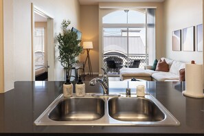 A modern kitchen with a double sink, two soap dispensers, and a single sponge. - Serene Zen' Quiet Garden View Resort Pool, Gym, Jacuzzi (Marina del Rey)
