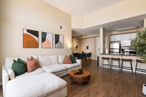 A modern living room with a sectional sofa, a round coffee table, and a dining area with a table and chairs.