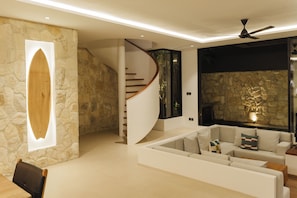Ein modernes Interieur mit einer Steinwand, einem Holzesstisch, einem weißen Sofa und einer Treppe.