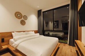 Ein modernes Hotelzimmer mit einem großen Bett, einem Holzkopfende, einem Fenster mit Vorhängen und Blick auf ein weiteres Zimmer.