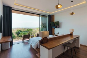 A modern hotel room with a large bed, a desk, and a TV mounted on the wall. - Villa Santi Bayu by Alfred in Bali (Pecatu)