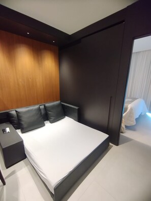 Ein modernes Schlafzimmer mit einem großen Bett, einem dunklen Kopfteil und einem Nachttisch.