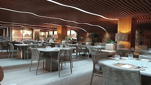 Un restaurante moderno con mesas redondas y sillas de mimbre, que destaca por un diseño de techo original y luz natural.