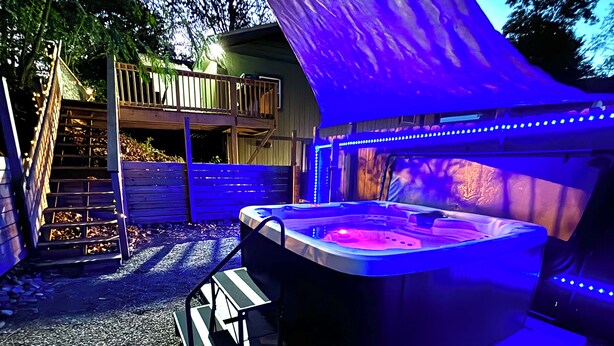 Uma banheira de hidromassagem com deck de madeira e área coberta com luzes LED azuis.
