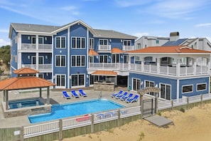 A two-story house with a swimming pool, multiple balconies, and a covered patio area. - The Regency | Oceanfront | Private Pool (Virginia Beach)