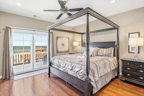 A four-poster bed with a view of the ocean through a sliding glass door. - The Regency | Oceanfront | Private Pool (Virginia Beach)