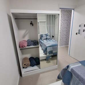 A bedroom with a wardrobe, a bed, and a mirror.