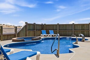 A swimming pool with a wooden deck, lounge chairs, and a wooden fence. - The Regency Royale | Oceanfront | Private Pool (Virginia Beach)