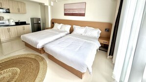 Una camera d'albergo con due letti, angolo cottura e vista sulla spiaggia.