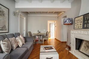 Un soggiorno con un divano grigio, un caminetto e una zona pranzo sullo sfondo.