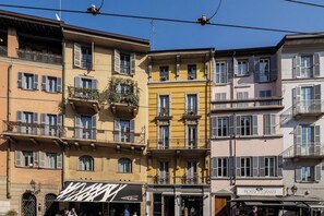 Una fila di edifici a più piani con balconi e tende da sole, caratterizzata da negozi con insegne.
