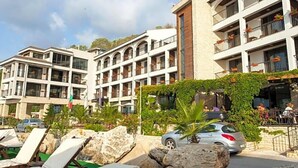 A hotel with multiple balconies, outdoor seating, and a pool area with lounge chairs. - Regina Maria (Balchik)