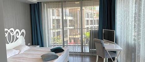 A hotel room with a bed, a desk, and a television.