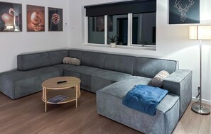 A modern living room with a grey sectional sofa, a round coffee table, and a floor lamp. - Gorgeous home in Ebeltoft with sauna (Ebeltoft)