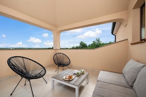 A balcony with a sofa, two chairs, a table, and a view of the landscape. - Villa Nina u Poreču, Istra by Istrabook (Poreč)
