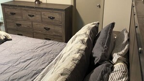 Un dormitorio con cama, cómoda y televisor montado en la pared.