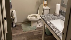Un baño con inodoro, lavabo y un cuadro en la pared.