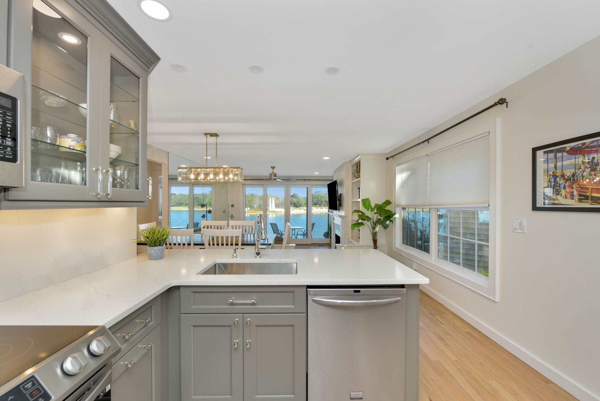 A modern kitchen with a central island, built-in appliances, and large windows overlooking a body of water.