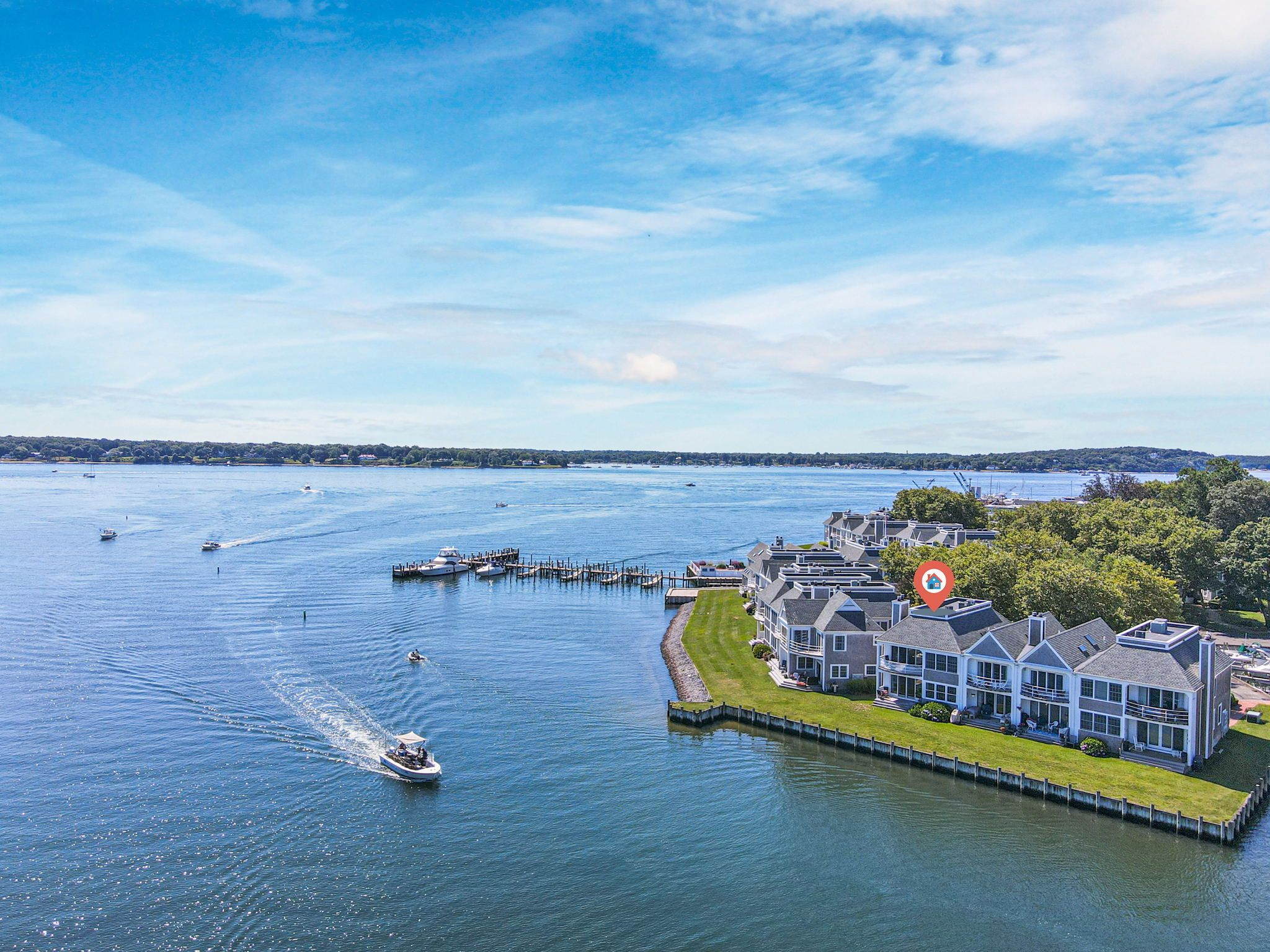 A waterfront property with a dock, boats, and a large house with multiple stories.