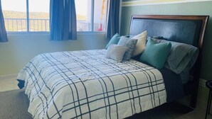 Quarto com cama, cortinas, ar condicionado e vista para o exterior.