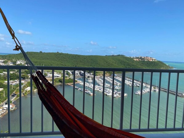 A hammock on a balcony overlooking a marina with boats and a hilly landscape in the background. - Slow Down & Relax Ocean, Marina, and Mountain Views! (Fajardo)